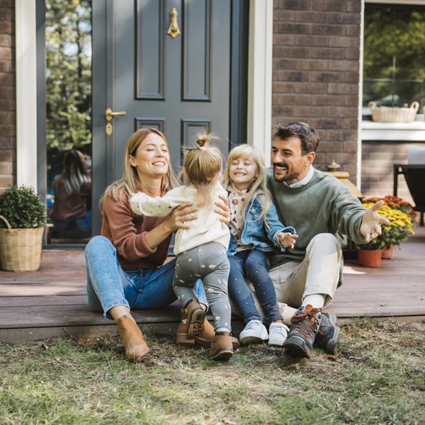 family of four sitting in front of home